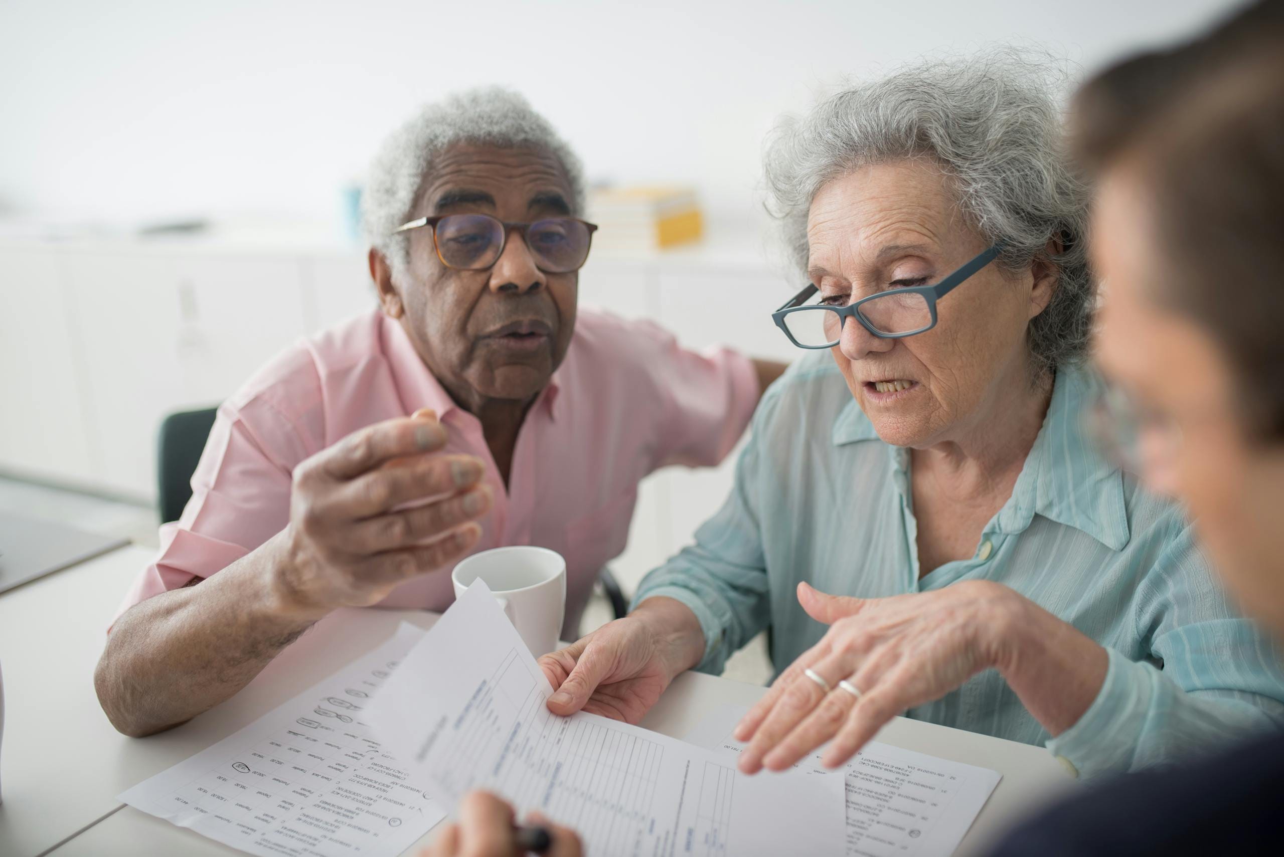 Elderly couple discussing Medicare cost planning with a consultant in an office setting.